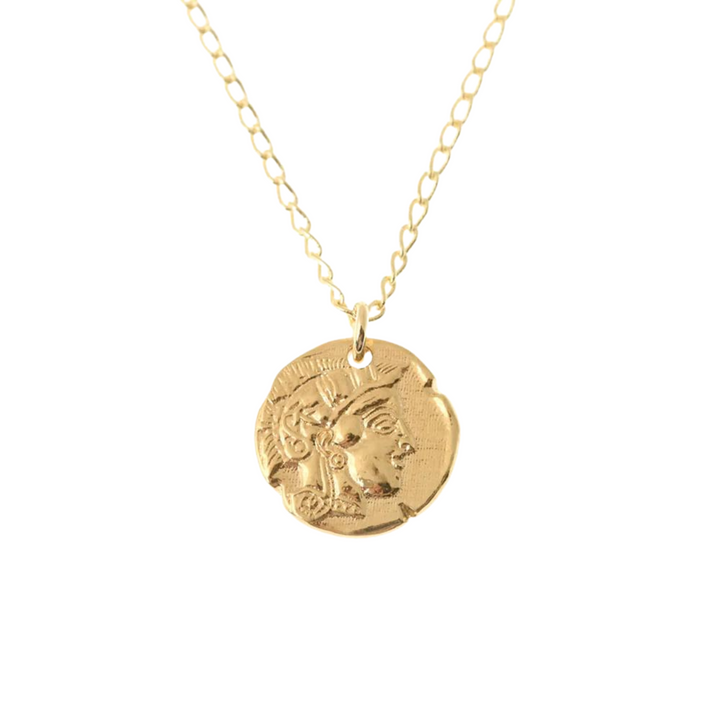 The Athena Coin Necklace Gold by Andrea Mears Jewellery is a gold-plated chain necklace with a round pendant featuring an embossed design. The pendant depicts an ancient Athena coin, showcasing intricate detailing around the edges. The chain has oval links, and the overall design has a vintage aesthetic rich in symbolism.