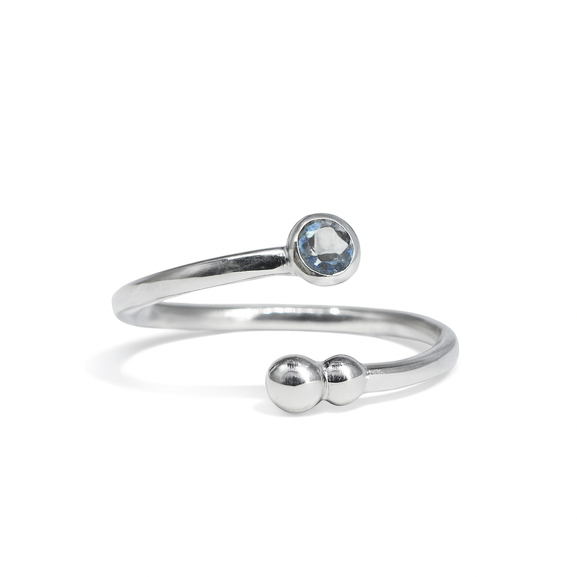 The Bauble & Stone Ring by Watermelon Tropical is a minimalist silver open band with a round blue quartz on one end and two small silver beads on the other, shown on a white background—ideal for handmade jewellery lovers.