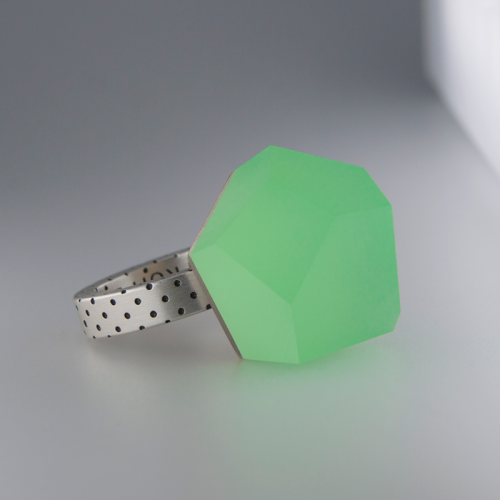 A close-up image of the Fruit Bijoux Ring Top VU Crystals Flash Green set on a sterling silver ring with a dotted design on the band. The ring top is showcased beautifully against a neutral, light-colored surface with a soft shadow.