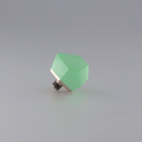 A small, hexagonal green object with a metallic screw base, featuring a ring top adorned in 24ct gold-plated detailing. The background is a plain, light gray gradient surface. The object appears to be a Fruit Bijoux Ring Top VU Crystals Flash Green from Fruit Bijoux.