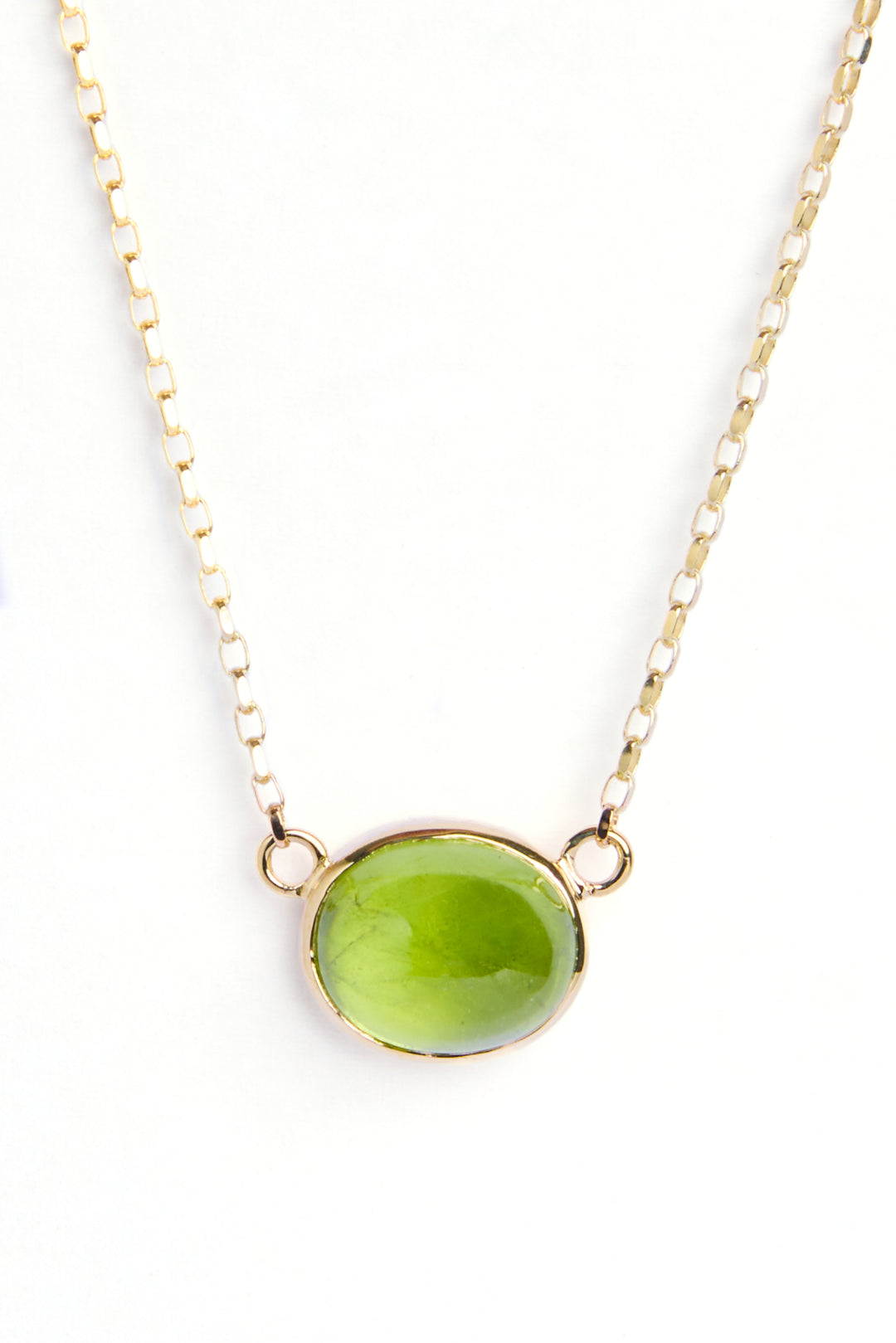 The 9ct yellow gold chain is 18 inches in length with an oval shaped peridot cabochon, which is a moss green stone, and is bezel set in 9ct yellow gold.