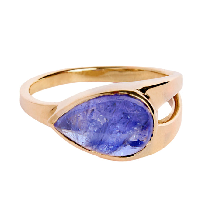 9ct yellow gold ring with teardrop shaped cabochon Tanzanite, which is a dark blue purple stone, bezel set in 9ct yellow gold. Irregular shaped band, tapers from a thicker width with cut-out detail and tapers down to a thinner band.