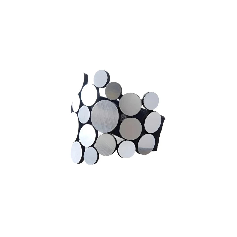 The Abstraction Fizz Bracelet by Iskin Sisters, featuring an array of circular, reflective silver discs in varying sizes . The black bracelet  boasts a modern, geometric design.