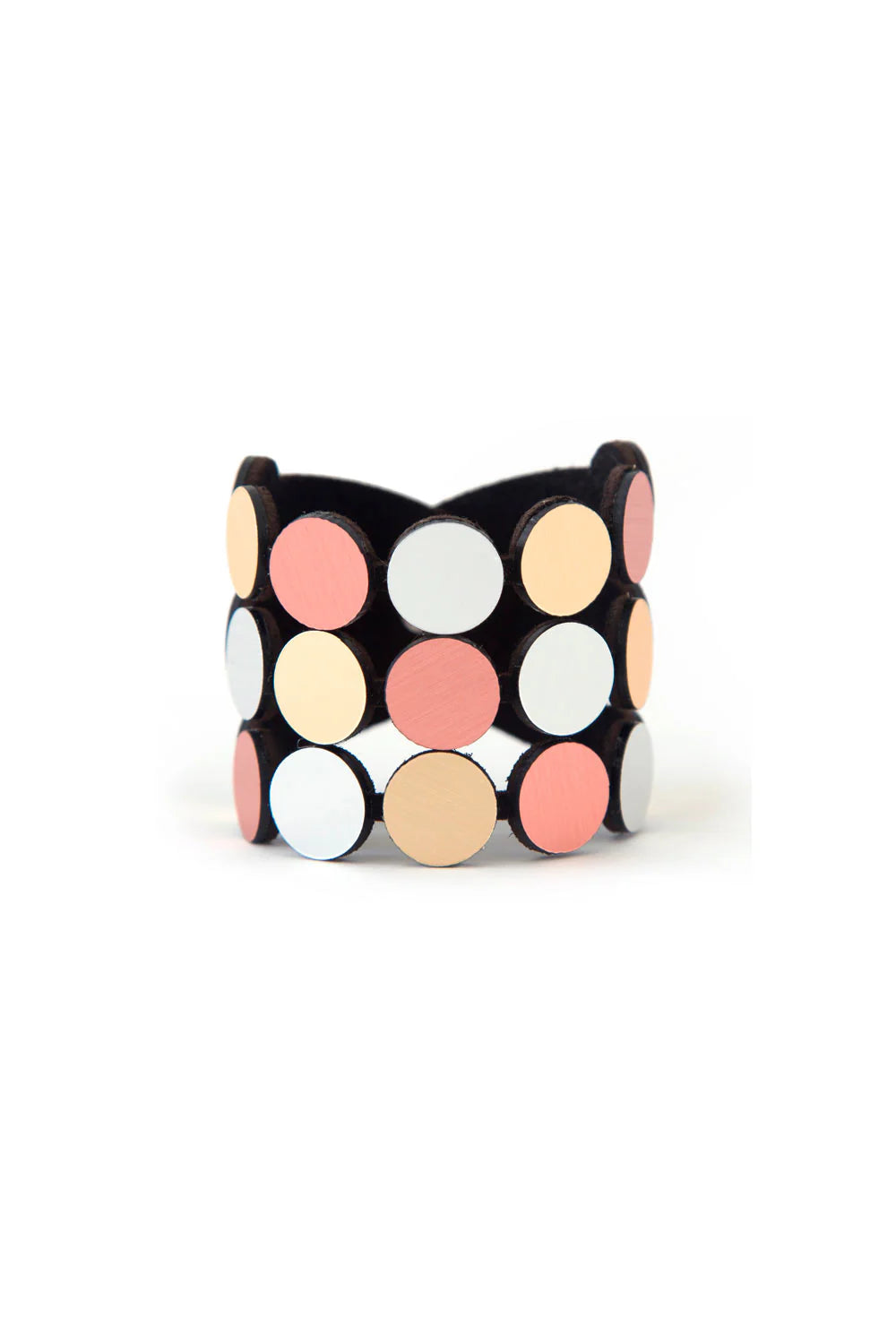 The Abstraction 3 Strand Bracelet by Iskin Sisters is an elegant piece of jewelry featuring circular decorations in pastel colors. The circles are arranged in three rows with shades of white, pink, and peach, beautifully contrasting against a dark base.