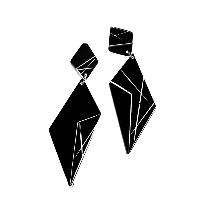 A pair of geometric black Alicia Earrings by Alex + Svet featuring large diamond shapes with angular, intersecting silver lines. The earrings are attached to smaller, similarly designed diamond shapes that connect to the earring hooks. These minimalist graphic Alicia Earrings have a modern aesthetic with unique hand-drawn patterns.