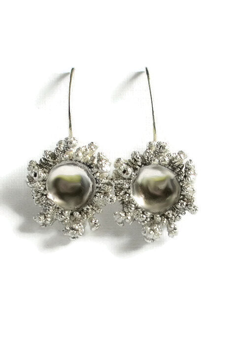 Spore Drops Silver Earrings by Abbie Dixon featuring round, pearl-like centers surrounded by intricate, textured designs resembling coral or floral patterns. These unique jewelry pieces have hook-style backs for easy wear. Made from sterling silver, the earrings stand out beautifully against a white background.