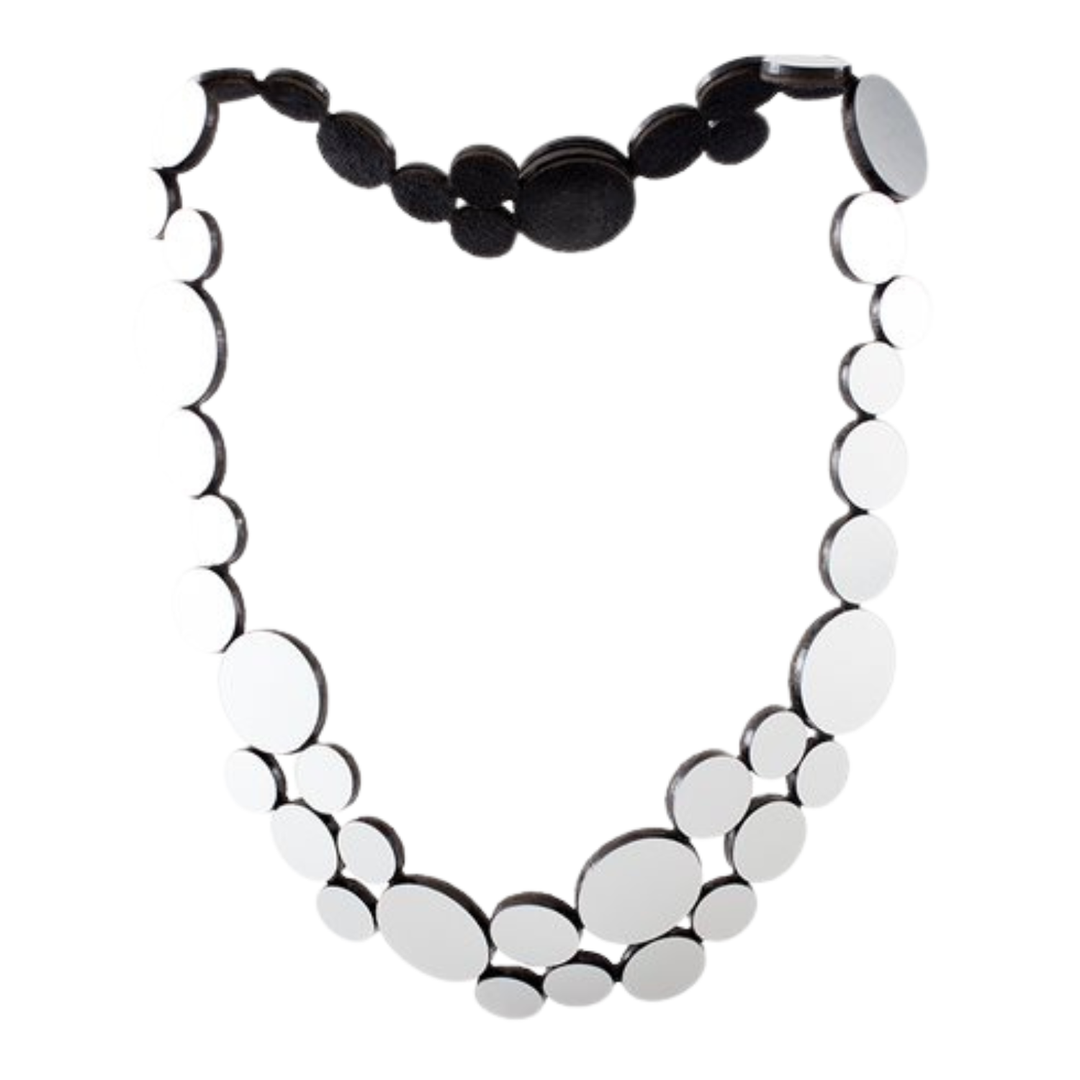 The Abstraction Fizz Silver Necklace by Iskin Sisters features two rows of geometric, mirror-like silver discs in varying sizes on a black backing with a circular clasp—an eye-catching statement piece for any occasion.