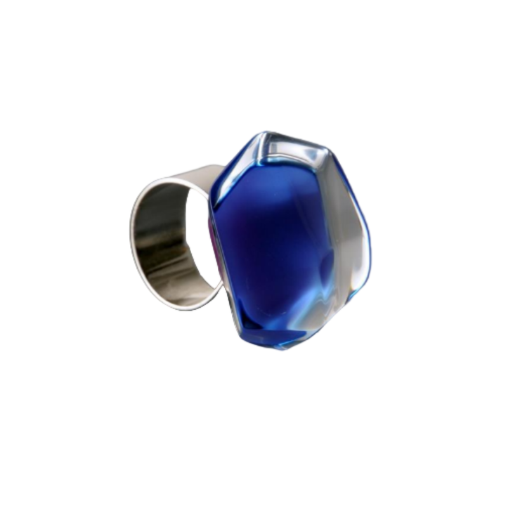 The Acrylic Dark Blue Ring by MX.design features a large blue and clear acrylic gemstone on an adjustable sterling silver band, shown against a white background—ideal for fans of bold MX.design accessories.