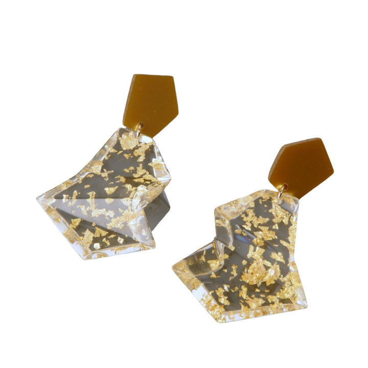 Presenting the Acrylic Gold & Clear Earrings by MX.design: These geometric earrings feature brown hexagonal studs connected to irregularly shaped translucent dangles with embedded gold flakes. The earrings are elegantly displayed on a dark gray background.