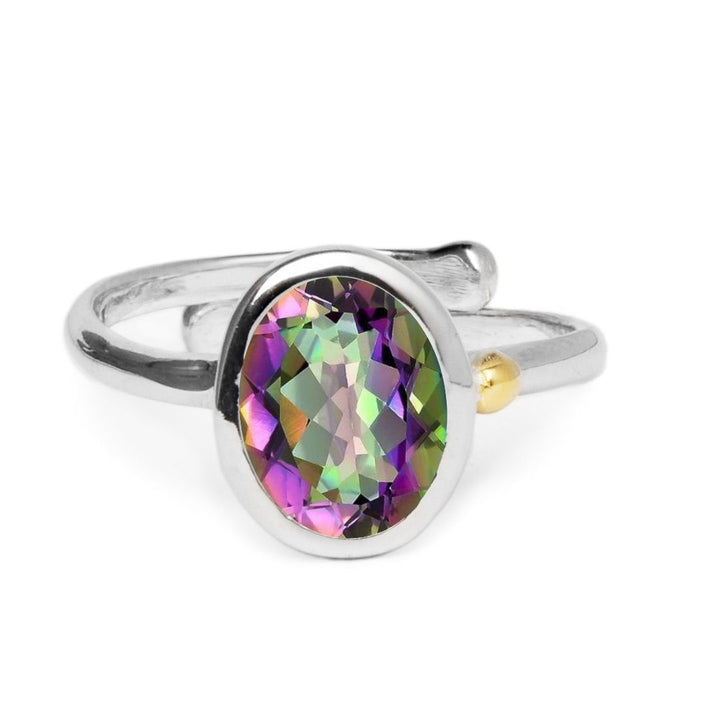 The Adjustable Dream Ring by Gallardo & Blaine Designs showcases a large oval, multicolored gemstone in green, purple, and gold. Crafted in sterling silver with a twisted band and small gold accent, it offers both elegance and minimalist style for versatile wear.