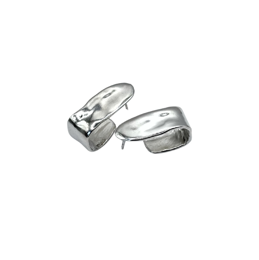 The Alma Square Earrings by Inó Jewellery are asymmetrical, chunky sterling silver pieces with a smooth, wavy surface, highlighting unique handmade Dublin craftsmanship, shown against a white background.