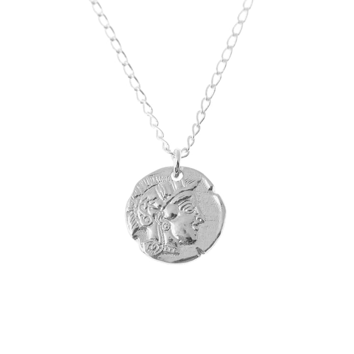 A sterling silver necklace featuring a round, textured medallion with an embossed design of a person's profile. The symbolic coin pendant, reminiscent of Athena goddess jewelry, hangs from a delicate chain with oval links. The Athena Coin Necklace Silver by Andrea Mears Jewellery is set against a plain white background.