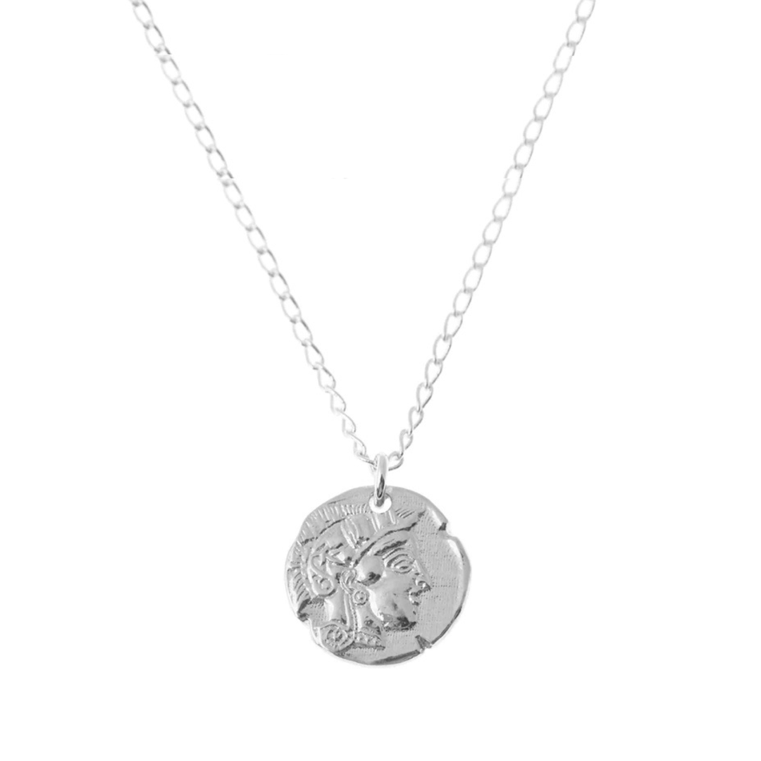 The Athena Coin Necklace Silver by Andrea Mears Jewellery features a delicate silver chain and a round pendant engraved with a classical figure in ancient Greek or Roman style.