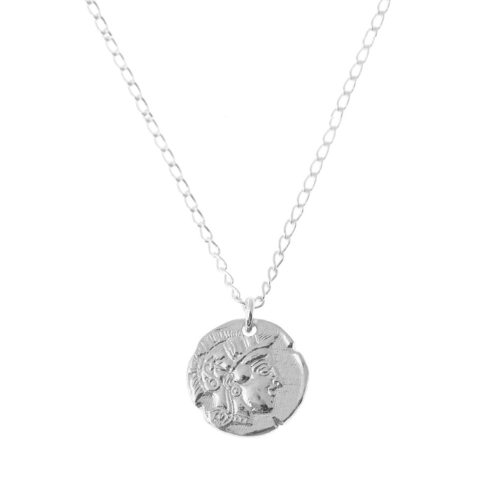 The Athena Coin Necklace Silver by Andrea Mears Jewellery features a delicate silver chain and a round pendant engraved with a classical figure in ancient Greek or Roman style.