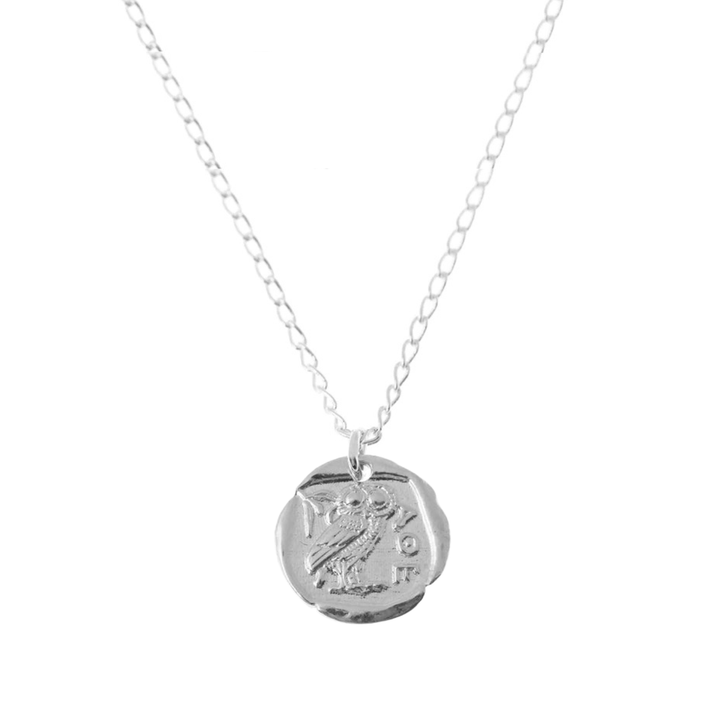The Athena Coin Necklace Silver from Andrea Mears Jewellery features a fine silver chain and a round pendant engraved with an owl and Greek letters, inspired by ancient Athena coin designs. Photographed on a plain white background.