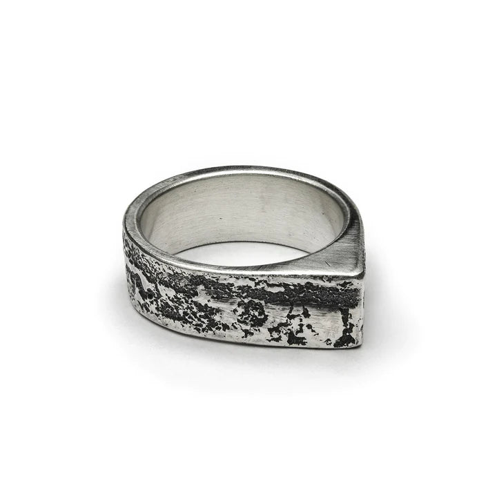 A uniquely designed Cursor Ring from Septentrion featuring a rugged, textured exterior is crafted from patinated 925 silver. The thick band has an uneven, weathered surface and a slightly asymmetrical shape, giving it that bold, rustic handmade jewellery look. The interior is smooth and polished for comfort.