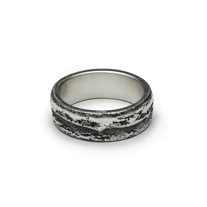 A textured 925 silver ring with a rugged, weathered appearance. The band features distressed finish and unique, dark irregular patterns, giving it a rustic look. The interior is smooth and polished. This piece of handmade jewelry, the Wide Ribbon Ring by Septentrion, is displayed on a plain white background.