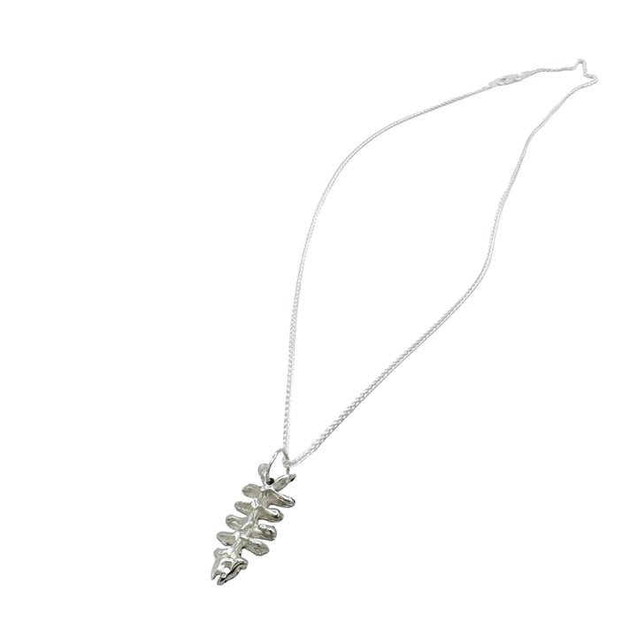The Baraka Pendant by Soufana Attia, a delicate silver necklace inspired by Arab symbols and Baraka jewelry, features a skeletal fish pendant and is displayed on a plain light gray background.