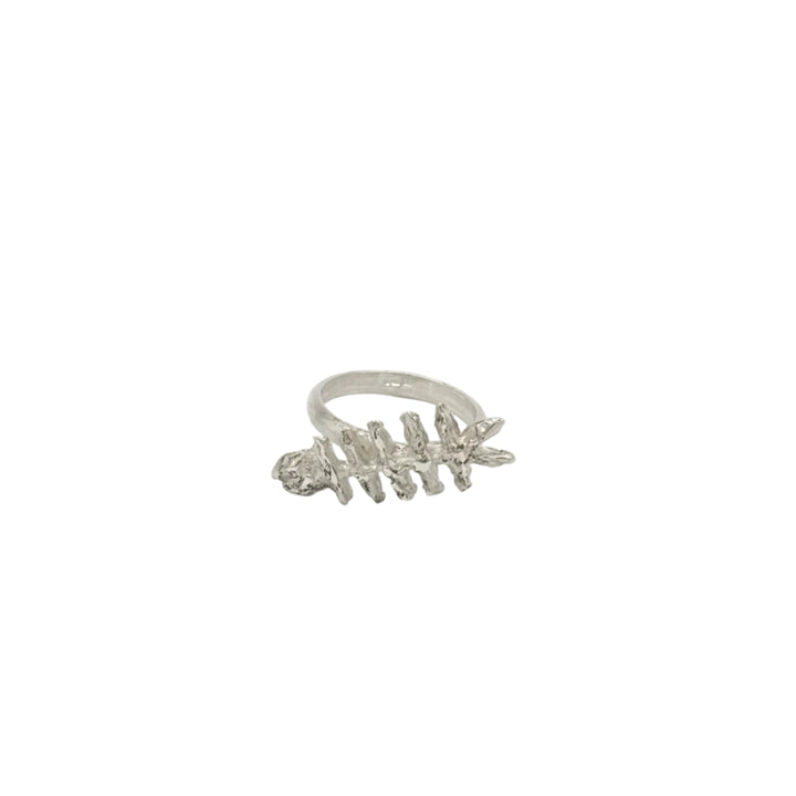 The Baraka Ring by Soufana Attia is a silver ring inspired by a fish skeleton, symbolizing protection and Baraka, shown upright on a simple white background.