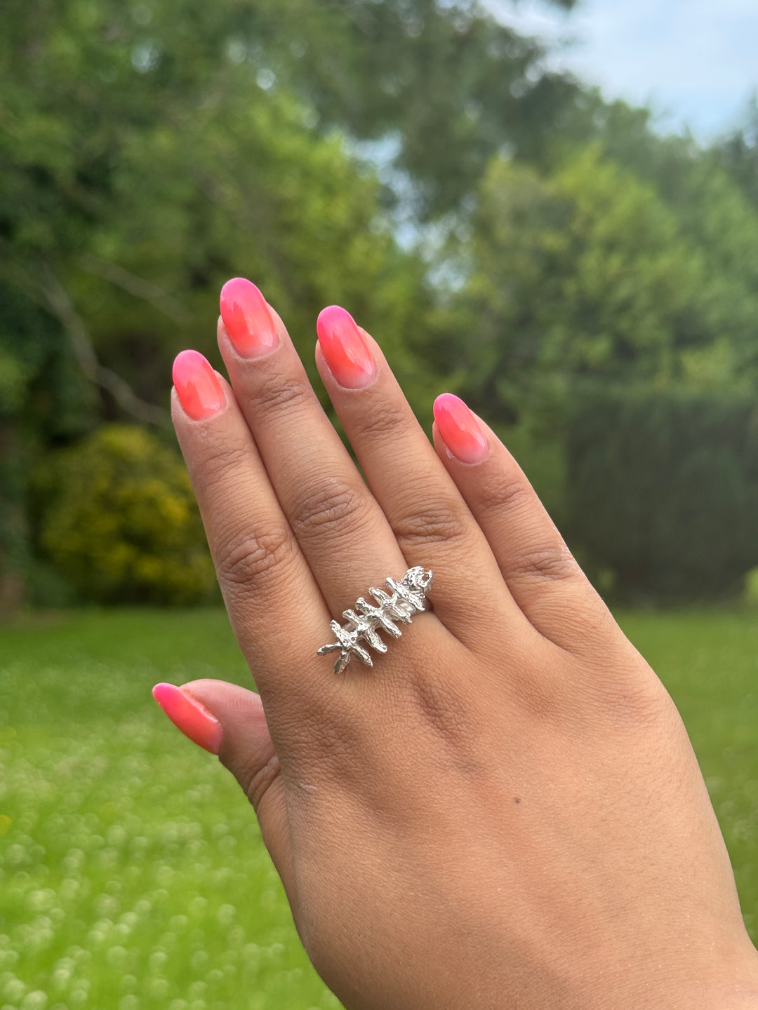 A hand  wearing the Soufana Attia Baraka Ring—a silver ring shaped like a skeletal fish, inspired by Arab symbols of protection and Baraka.