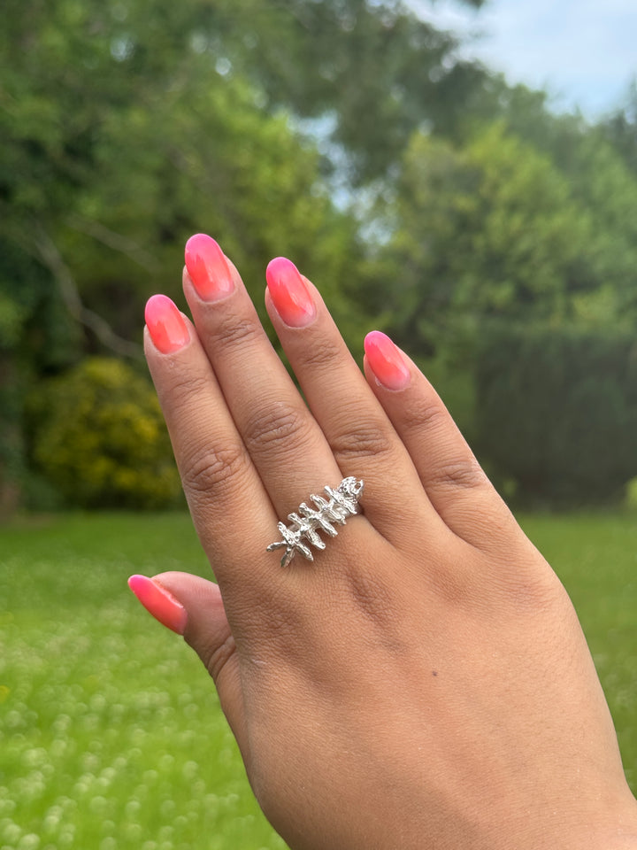 A hand  wearing the Soufana Attia Baraka Ring—a silver ring shaped like a skeletal fish, inspired by Arab symbols of protection and Baraka.
