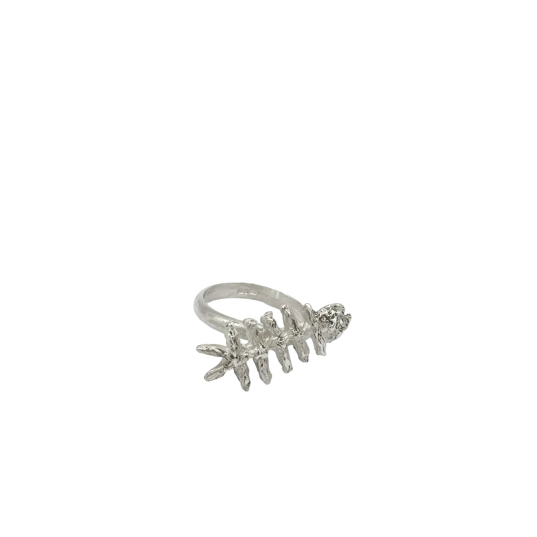 The Baraka Ring by Soufana Attia is a silver ring inspired by Arab symbols of protection and Baraka, designed to resemble a fish skeleton and shown on a plain white background.