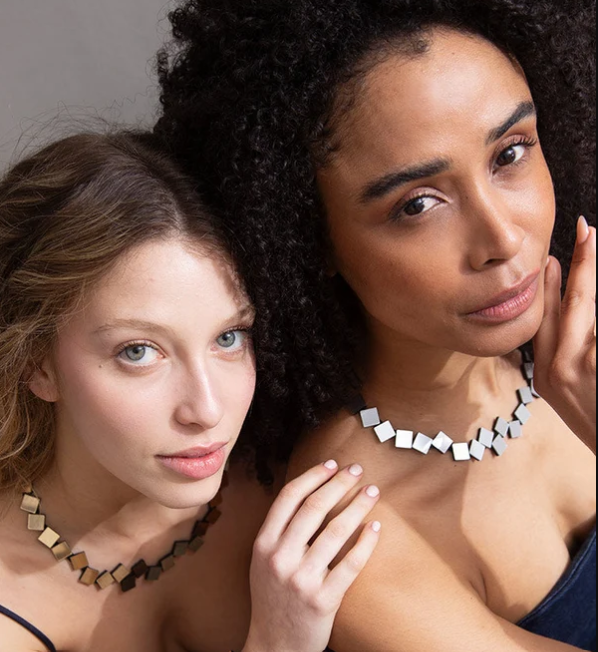 Two women wearing Bauhaus Round Squares Necklace - Silver jewelry pieces crafted from small, connected square metal tiles.
