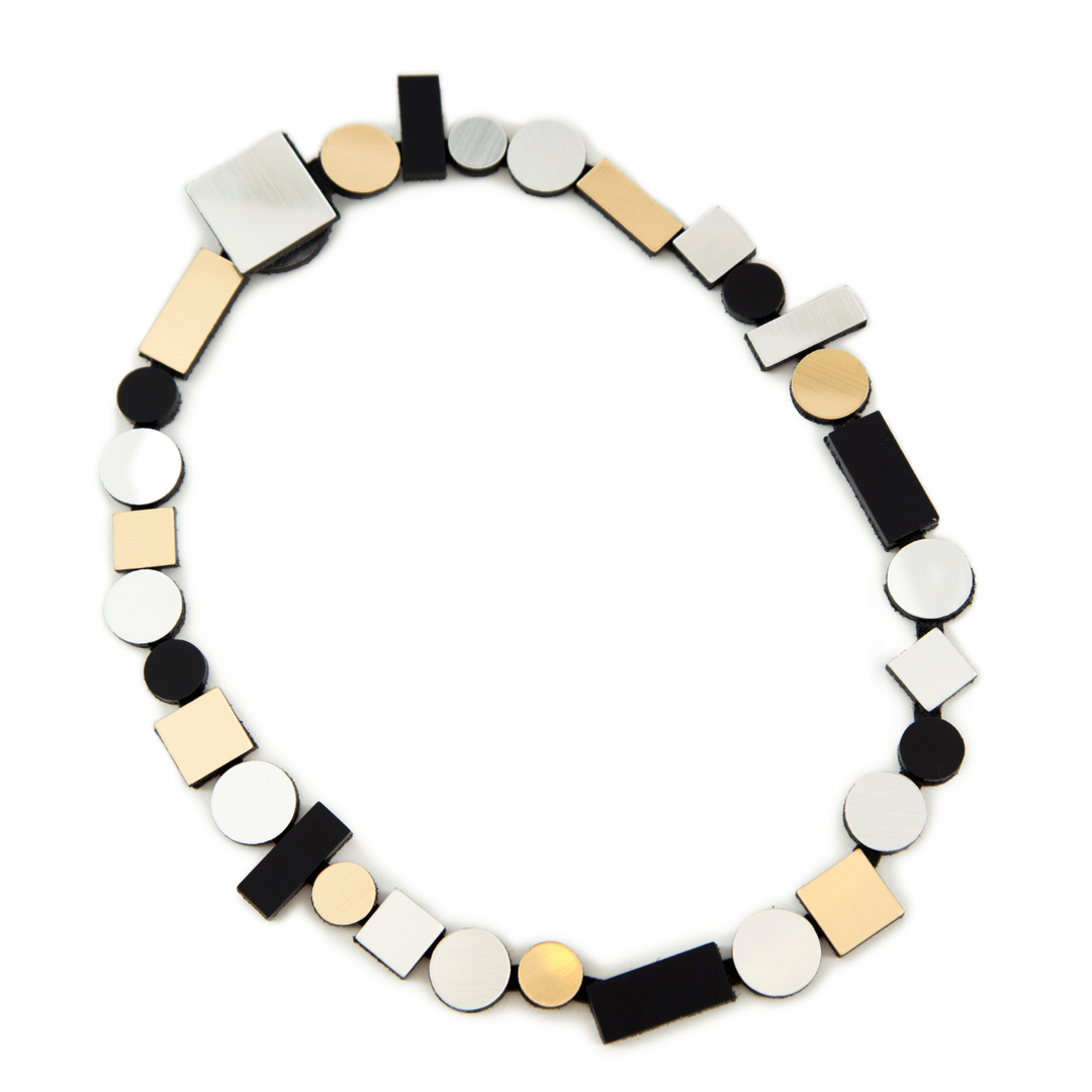 The Iskin Sisters Bauhaus Silver, Black & Gold Necklace showcases alternating geometric shapes—circles, squares, and rectangles—in silver, gold, and black for a modern minimalist look.