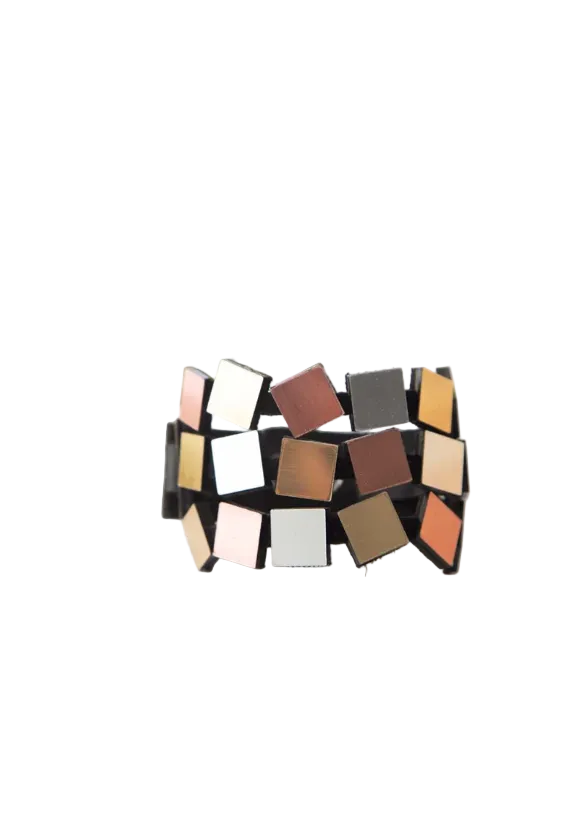 A wide cuff bracelet made of small square tiles in silver, gold and copper tones, displayed on a white surface.