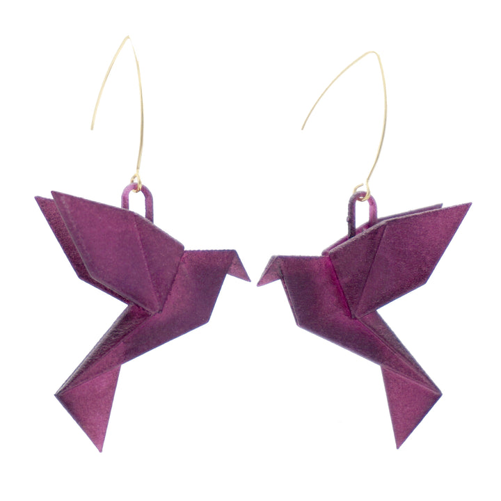 A pair of earrings shaped like origami hummingbirds, crafted from purple material with gold-colored hooks, is shown against a white background. The intricate folds and angles mimic the appearance of paper origami art, perfect for those who appreciate the beauty of 3D printed nylon jewellery. These are the Origami Bird Aubergine Earrings by Tochu-De.