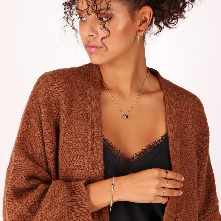 Woman wearing a brown cardigan over a black top on a white background