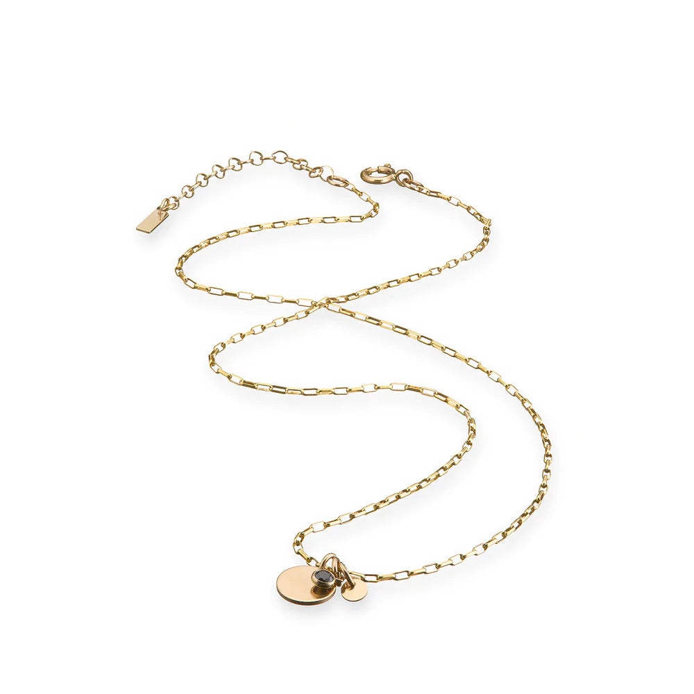 Gold necklace with circular pendants including black cubic zirconia on a white background. Link chain.