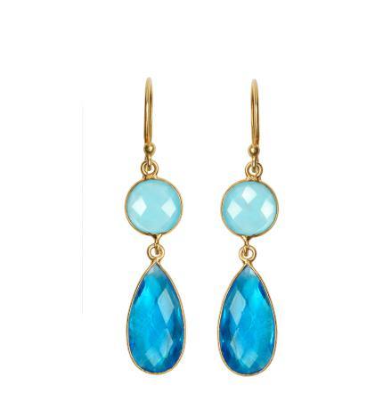 The Blue Orchid Earrings by Watermelon tropical are a pair of elegant gold vermeil earrings featuring a round light blue faceted gemstone at the top connected to a larger, teardrop-shaped dark blue faceted gemstone below. The gemstones, possibly blue quartz or agua chalcedony, are set in thin gold framing, giving them a delicate and refined appearance.