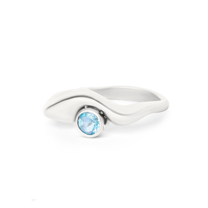 The Bough Ring by Madeleine Sculptural Jewellery features a modern wavy silver band with a round blue gemstone at the center. Handcrafted, this sleek piece highlights contemporary style and the stone's vibrant color.
