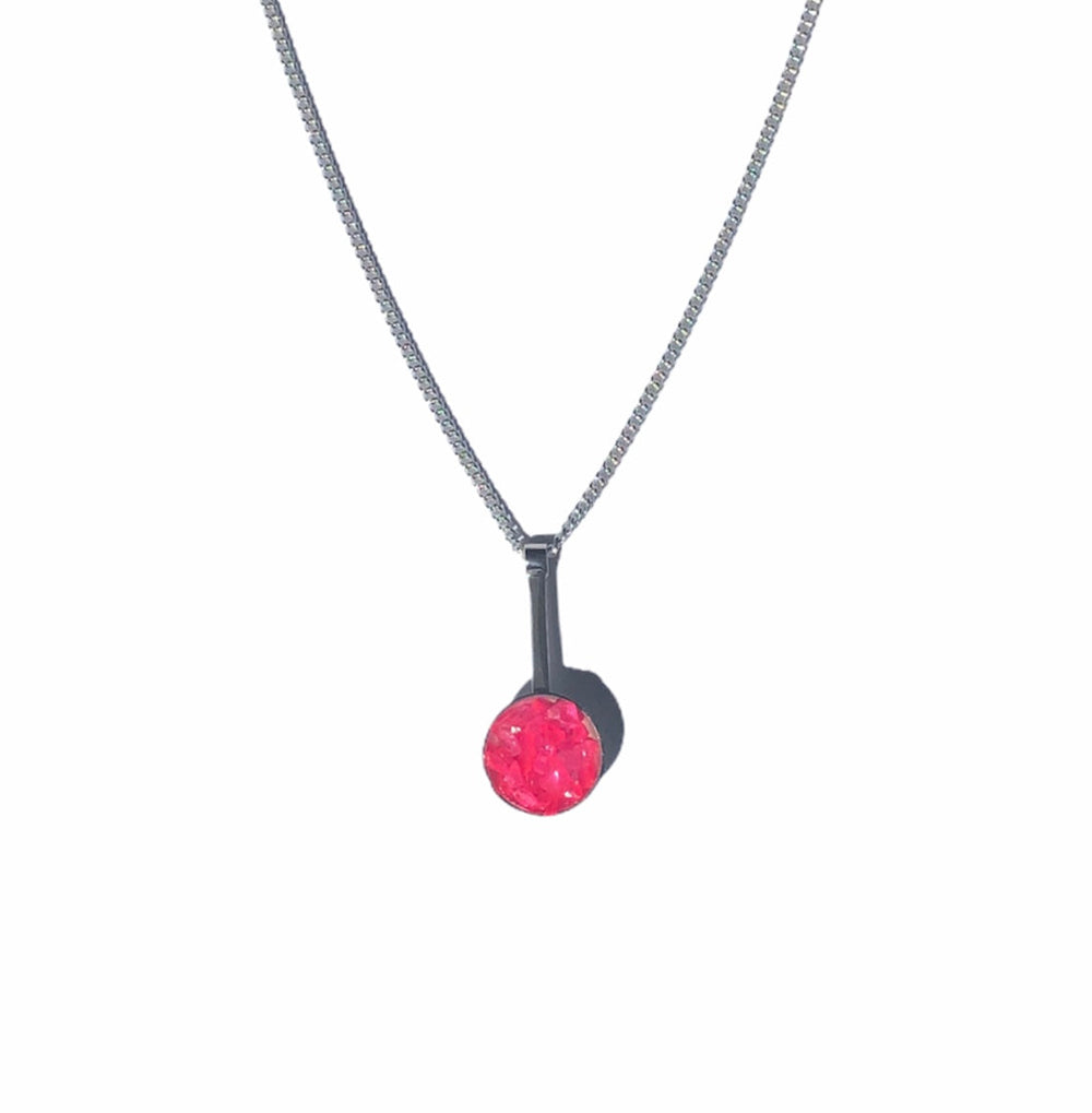 Introducing the Neon Dome Drop Pendant by Angela O'Keefe: a delicate silver necklace featuring a slender vertical bar pendant on a sterling silver chain, adorned with a single, round-cut pink or yellow gemstone at the bottom. The minimalist and elegant design highlights the beauty of the gemstone against a plain white background.