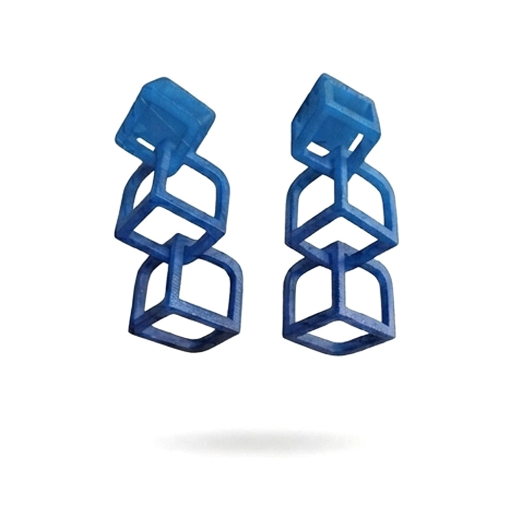 The Tochu-De Cubic Earrings Blue feature three connected open cubes in a vertical drop design. Displayed on a white background, these modern, 3D-printed geometric earrings make a unique statement.