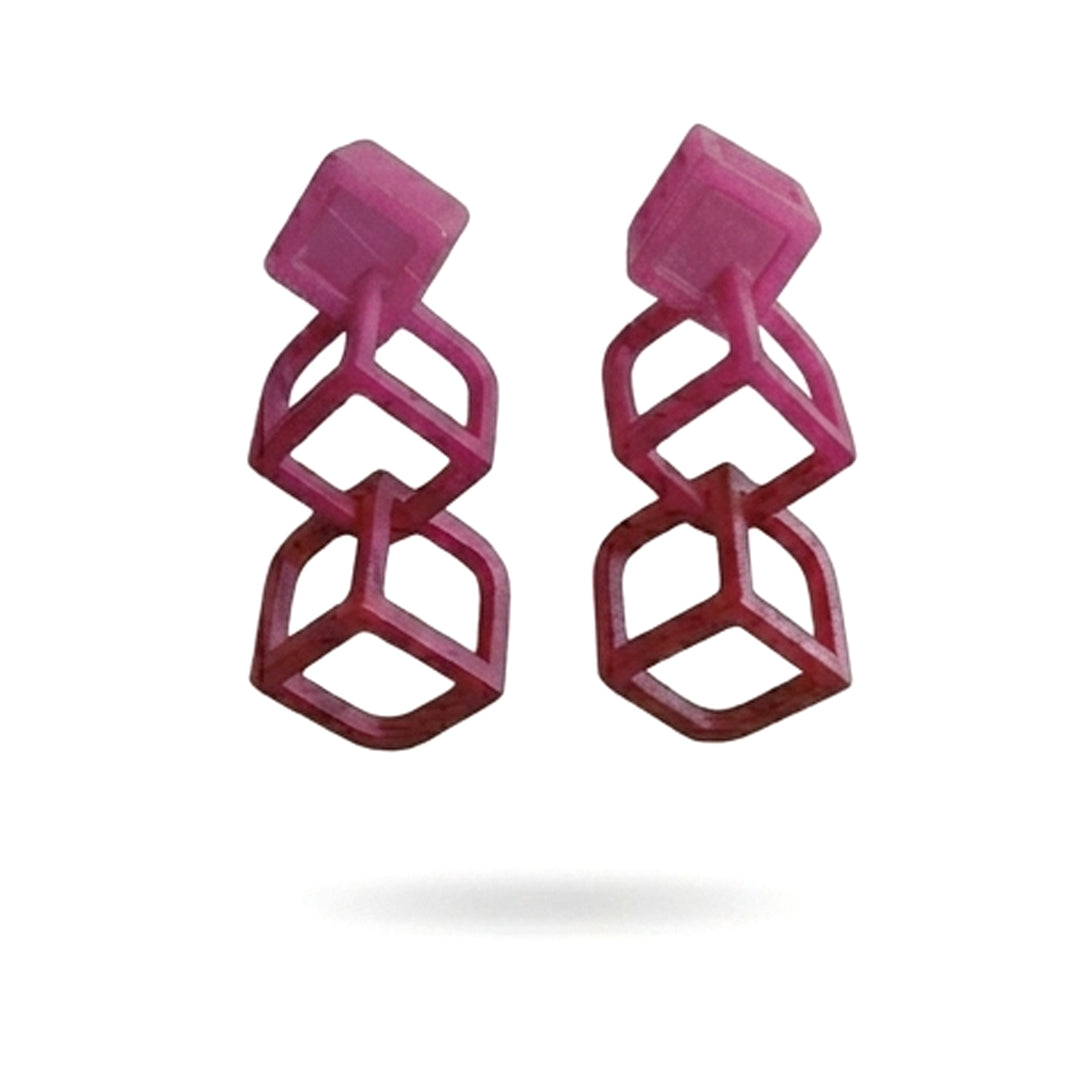 The Tochu-De Cubic Earrings Burgundy feature three vertically stacked, open-framed magenta cubes with silver studs, set against a plain white background.