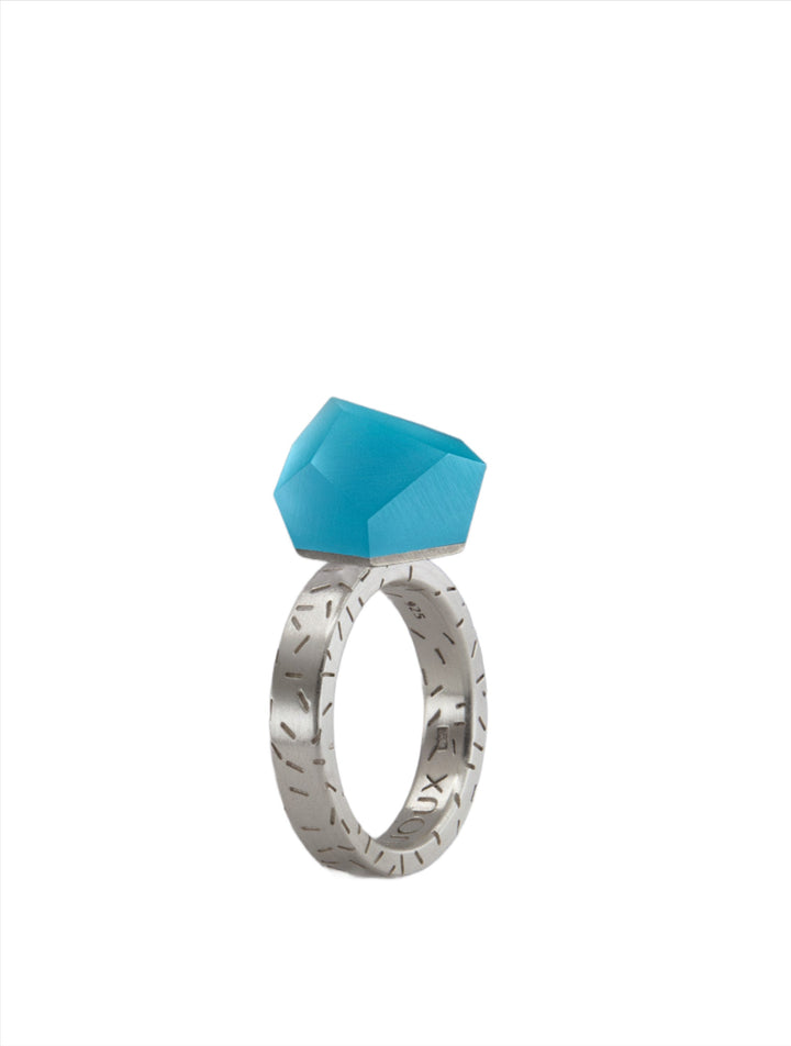 A Fruit Bijoux Fruit Bijoux Ring Top VU Crystals Capri Blue with etched patterns on the band and a large, faceted turquoise gemstone set atop a geometric structure. The ring is displayed against a plain white background.