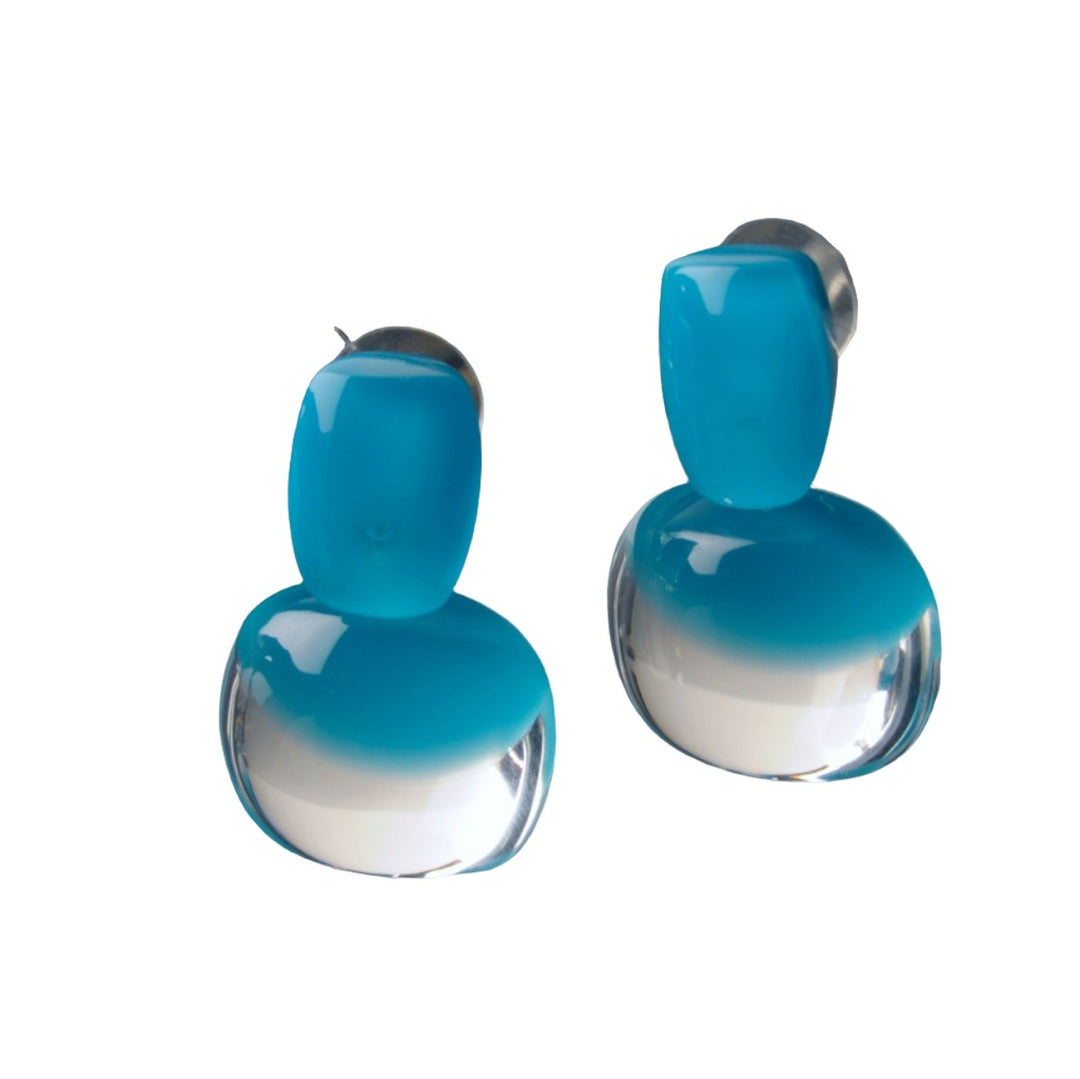 Introducing the Acrylic Capri Blue Earrings by MX.design, a stunning pair of acrylic earrings featuring a glossy capri blue that transitions into a clear base. These earrings boast a bulbous, rounded form with the top portion displaying a solid blue shape and the lower part transforming into a clear, rounded drop.