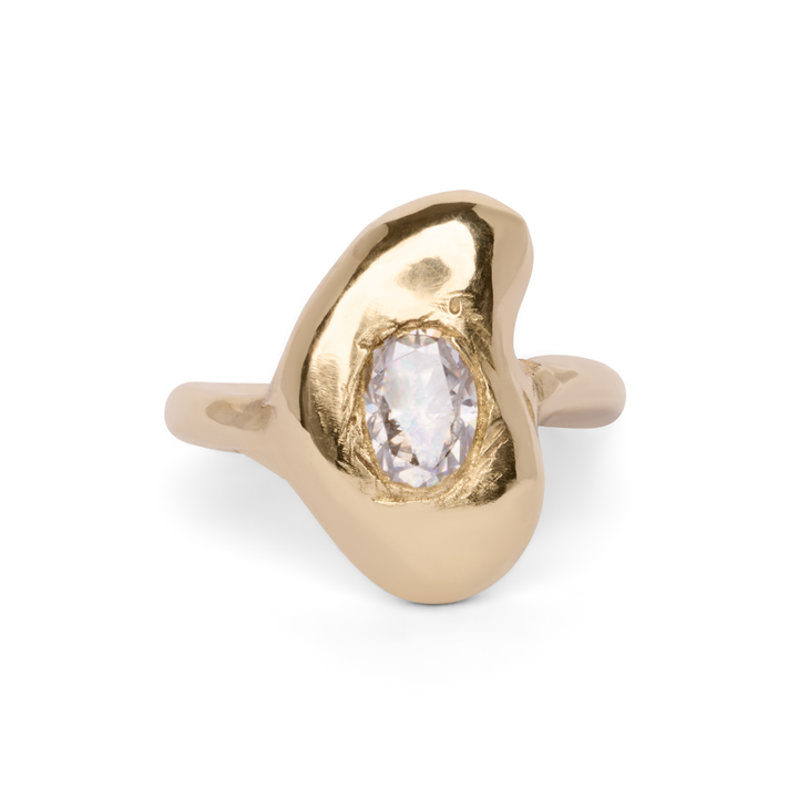 A gold Carraig Ring by Madeleine Blaine with an organic, asymmetrical design, featuring a clear, oval-shaped Irish stone set in the center.