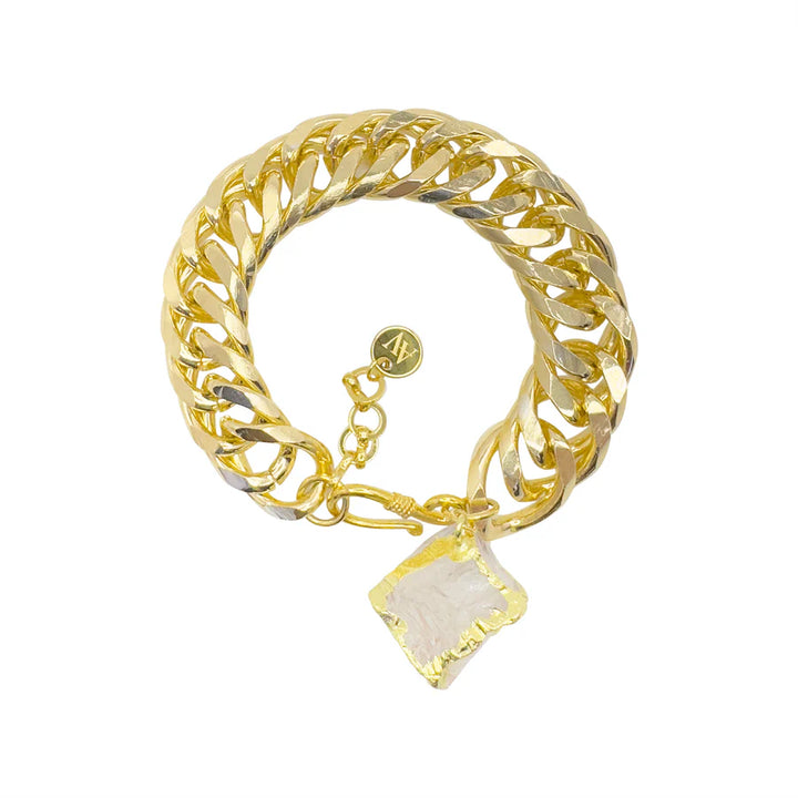The Carrie Bracelet by Aria V is handmade in Dublin—a chunky gold plated bracelet with a shiny finish, clear quartz pendant outlined in gold, and a small round gold charm near the clasp.