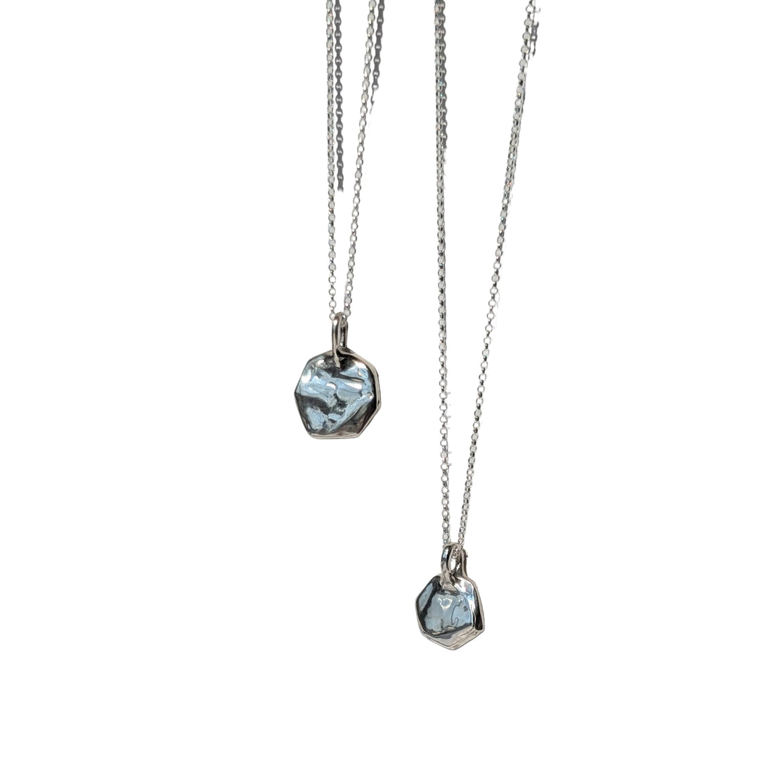Two Causeway Coastal Silver Pendants by Becca Calmont, each featuring a marbled blue and white stone set in a polygonal design, hang on recycled sterling silver chains—a stunning showcase of handmade Irish jewelry.