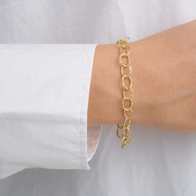 A person wearing a white long-sleeve shirt showcases the Watermelon tropical Chain Bracelet, a delicate handmade gold piece with large oval links on their wrist.