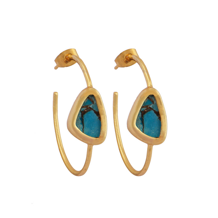 The Chloe Gold & Green Turquoise Hoop Earrings from Watermelon Tropical feature gold hoops with triangular blue Turquoise stones at the centre. The rustic appearance and dark striations of the stones enhance their natural beauty, while sterling silver prongs delicately secure them. These earrings boast a minimalist, elegant design that combines gold and black accents gracefully.