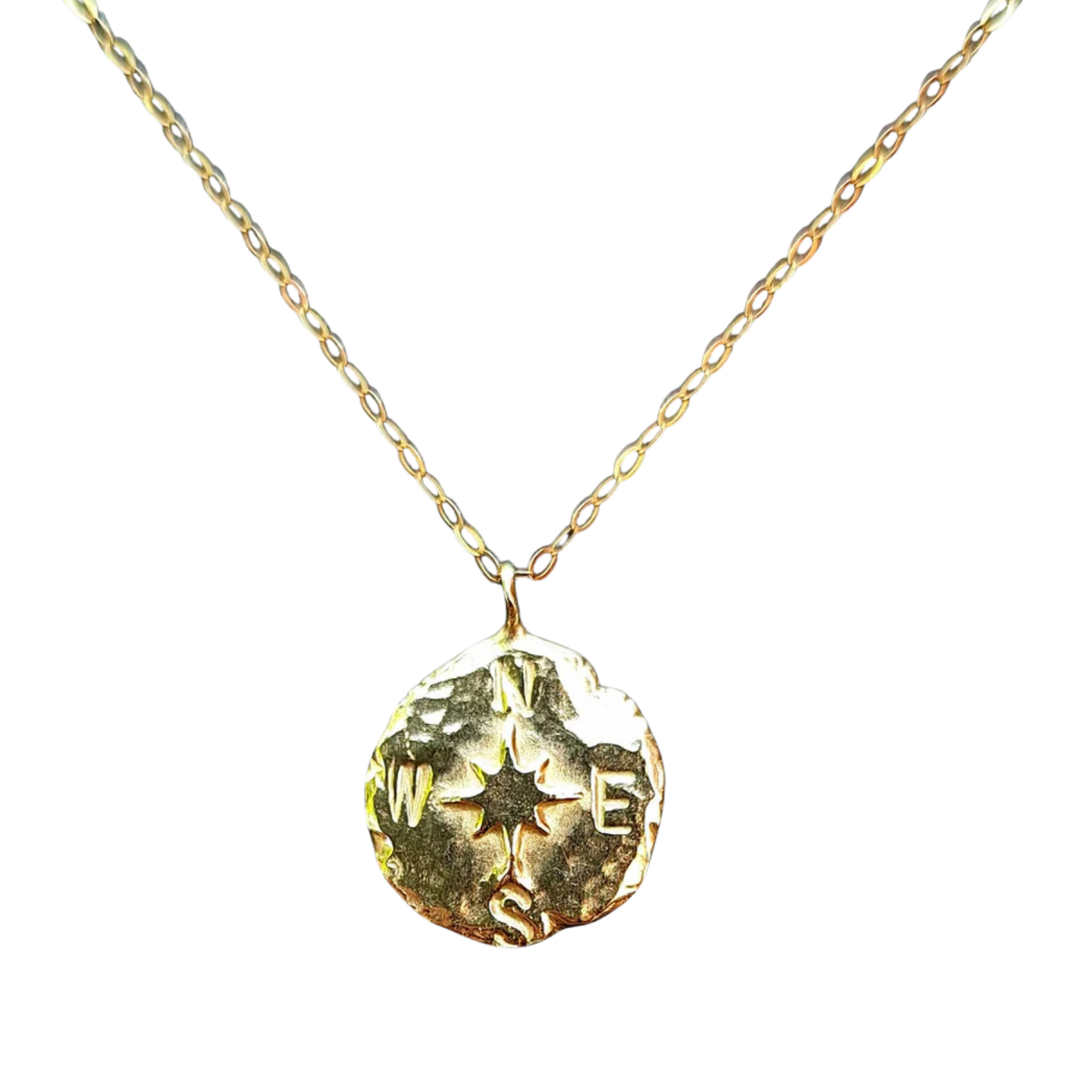 The Pale Raven Compass Coin Gold Plated Necklace features a chain-link design and a round, textured compass pendant engraved with a rose and the N, E, S, W cardinal directions.