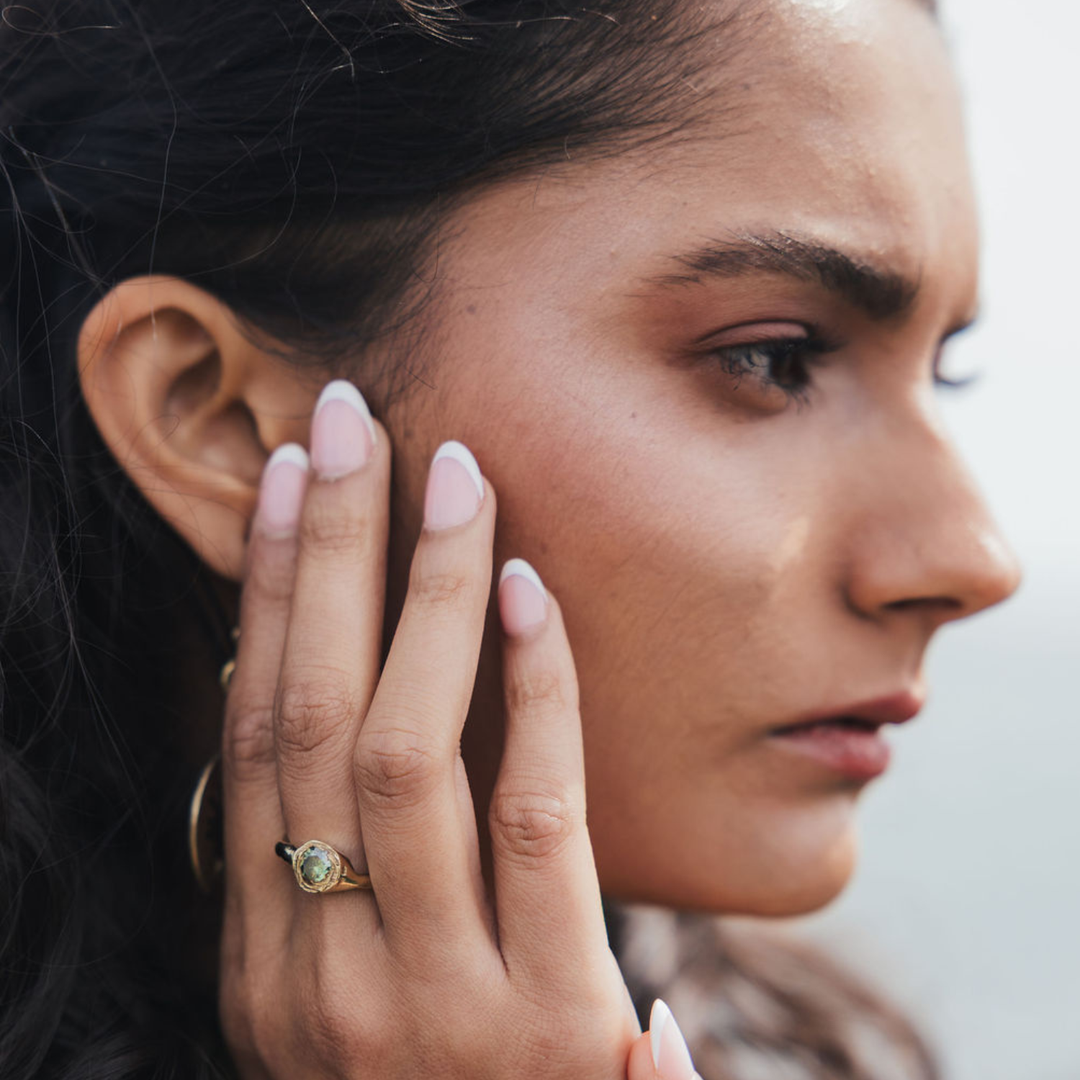 Delicate gold ring with minimalist design inspired by dawn sky aesthetics, shown on hand against soft background.
