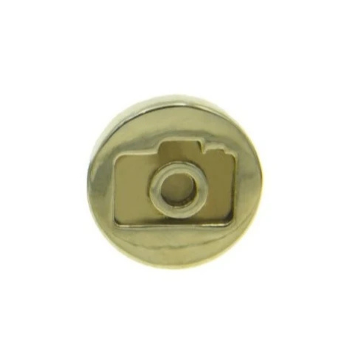 A round, gold-toned custom pin with an embossed design of a camera in the center. The Camera Lapel Pin by Millett Wade features a lens and a viewfinder, and it boasts a smooth, shiny surface.