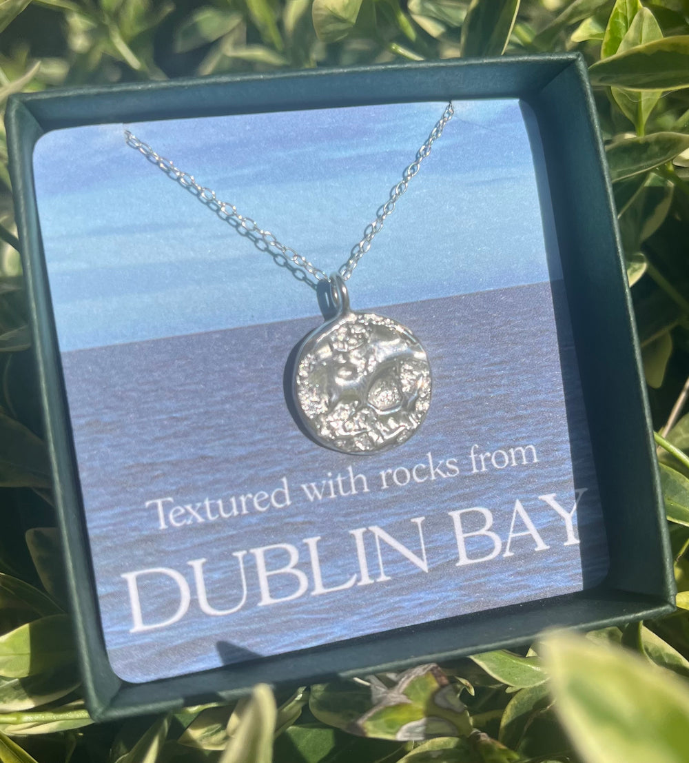 The Dublin Bay Silver Pendant by Ava Jane Jewellery is a handmade sterling silver necklace, beautifully boxed with a card reading "Textured with rocks from Dublin Bay"—a unique piece of Irish sea-inspired jewelry.