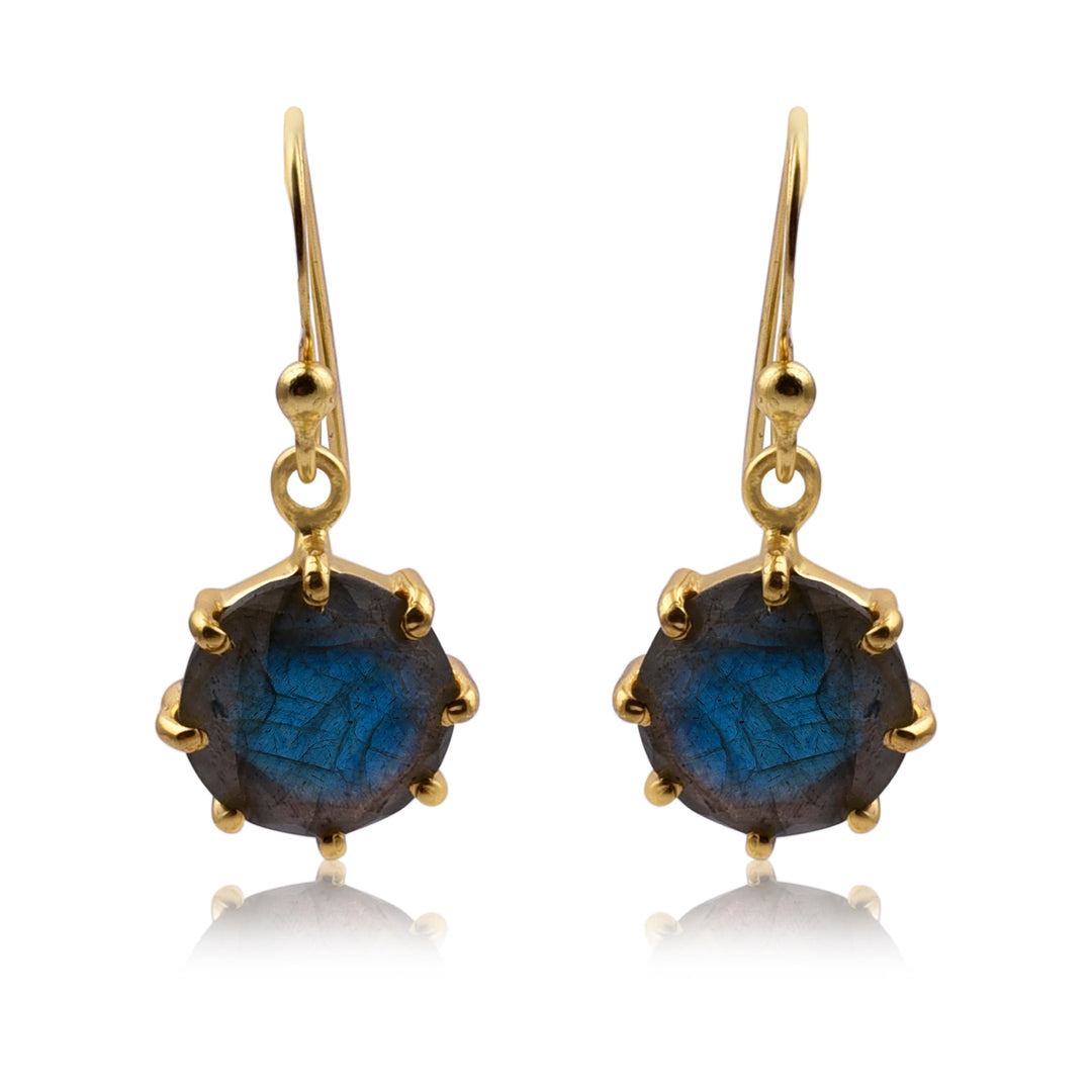 This image shows a pair of Labradorite Gold Dangles by Watermelon Tropical, featuring round, faceted blue gemstones held in gold prong settings. The stones have a marbled appearance and hang from delicate hooks. The handmade jewellery boasts a sophisticated and elegant design.