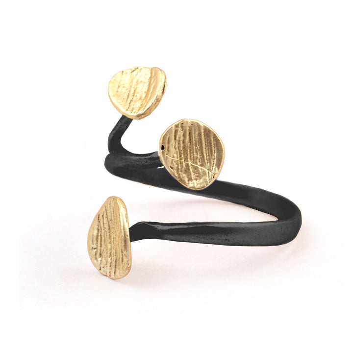 The Rachel Ring by Watermelon Tropical is an artistic, Egyptian-inspired ring with a black band that twists in a spiral shape, featuring three round, textured gold accents. The triple disc design is spaced along the length of the gold plated sterling silver band, creating a balanced and modern look against the plain white background.